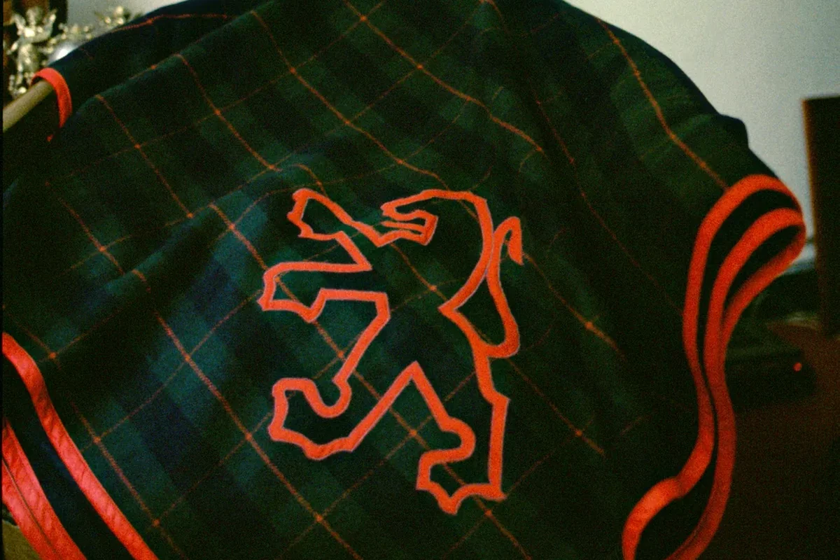 Housse en tissu écossais vert avec un lion brodé et un passepoil rouge, avant la pose sur la voiture