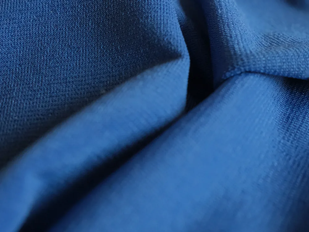 Tissu Lycra bleu froissé : la maille accroche la lumière et dessine des plis nets