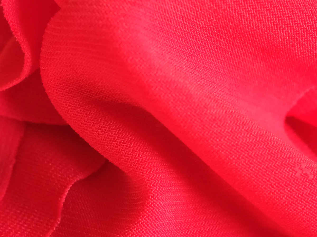 Gros plan du tissu Lycra rouge : maille fine à côtes serrées, surface lisse